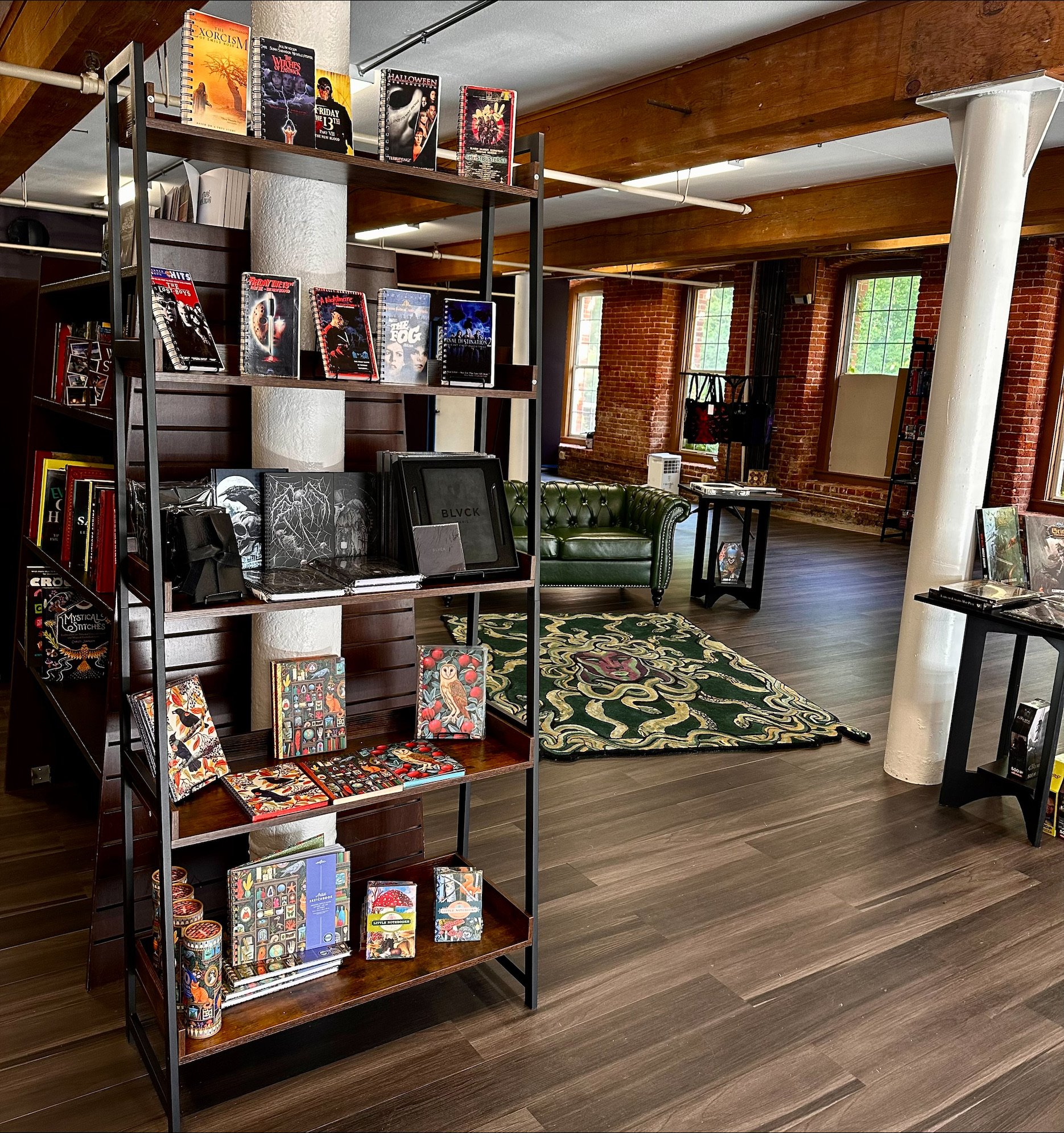 Merchandise display shelf with horror-themed journals and notebooks, green Chesterfield sofa visible in background